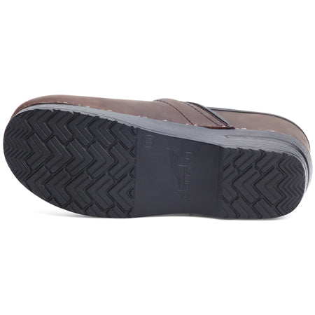 Brown shoe sole with a ridged, zigzag tread pattern and a logo imprinted in the center, typical of Dansko clogs known for their professional shoe appeal.