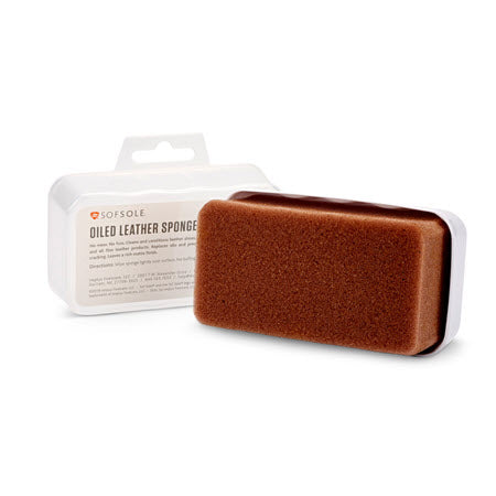 A brown leather care sponge in front of its white and clear packaging, labeled &quot;SOF SOLE OILED LEATHER SPONGE&quot; by Sof Sole. This essential tool cleans leather shoes effectively and is a must-have for fine leather products.