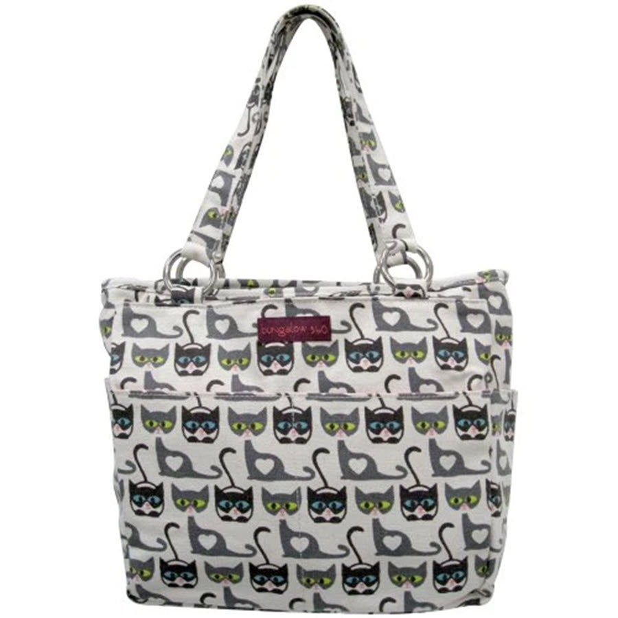 A white handbag with a pattern of gray and black cats wearing sunglasses. Featuring an exterior front pocket, this 100% vegan Bungalow 360 BUNGALOW 360 POCKET BAG CATS POCKET BAG has two handles and showcases playful animal theme prints.