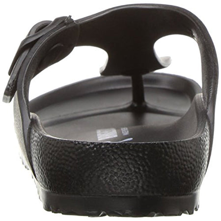 A close-up view of the back of a black BIRKENSTOCK GIZEH EVA BLACK - WOMENS, displaying textured material and a back strap with a side buckle. The Birkenstock sandal also features a toe separator at the front, made from waterproof EVA foam for added durability.