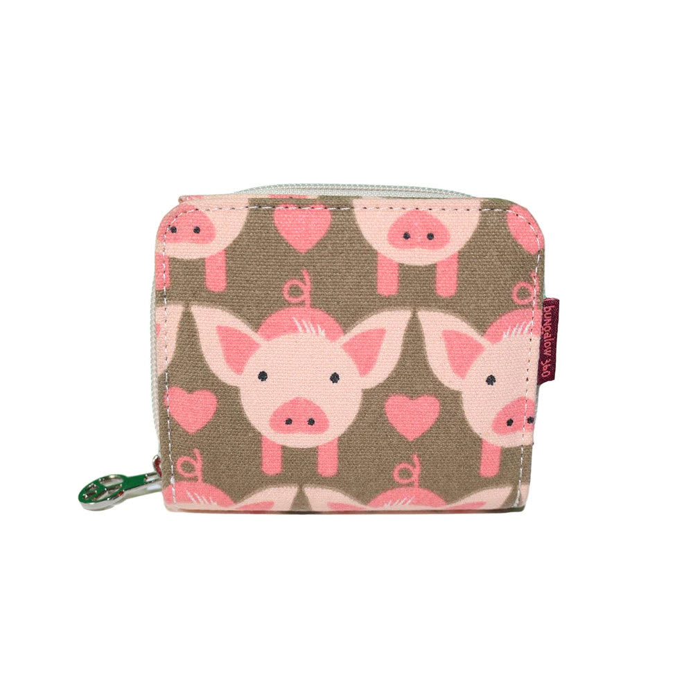 The Bungalow 360 BUNGALOW 360 BILLFOLD WALLET PIG featuring a pink colored pig pattern and hearts on a beige and green natural cotton canvas, with a zipper closure and tag.