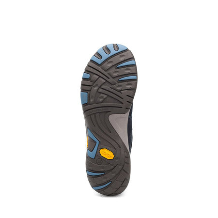 The bottom view of a shoe sole showcases black and blue tread patterns, featuring a yellow logo near the heel. Designed for durability, it incorporates a Vibram rubber outsole and offers excellent arch support. The product is the DANSKO PAISLEY MILLED NUBUCK NAVY - WOMENS by Dansko.