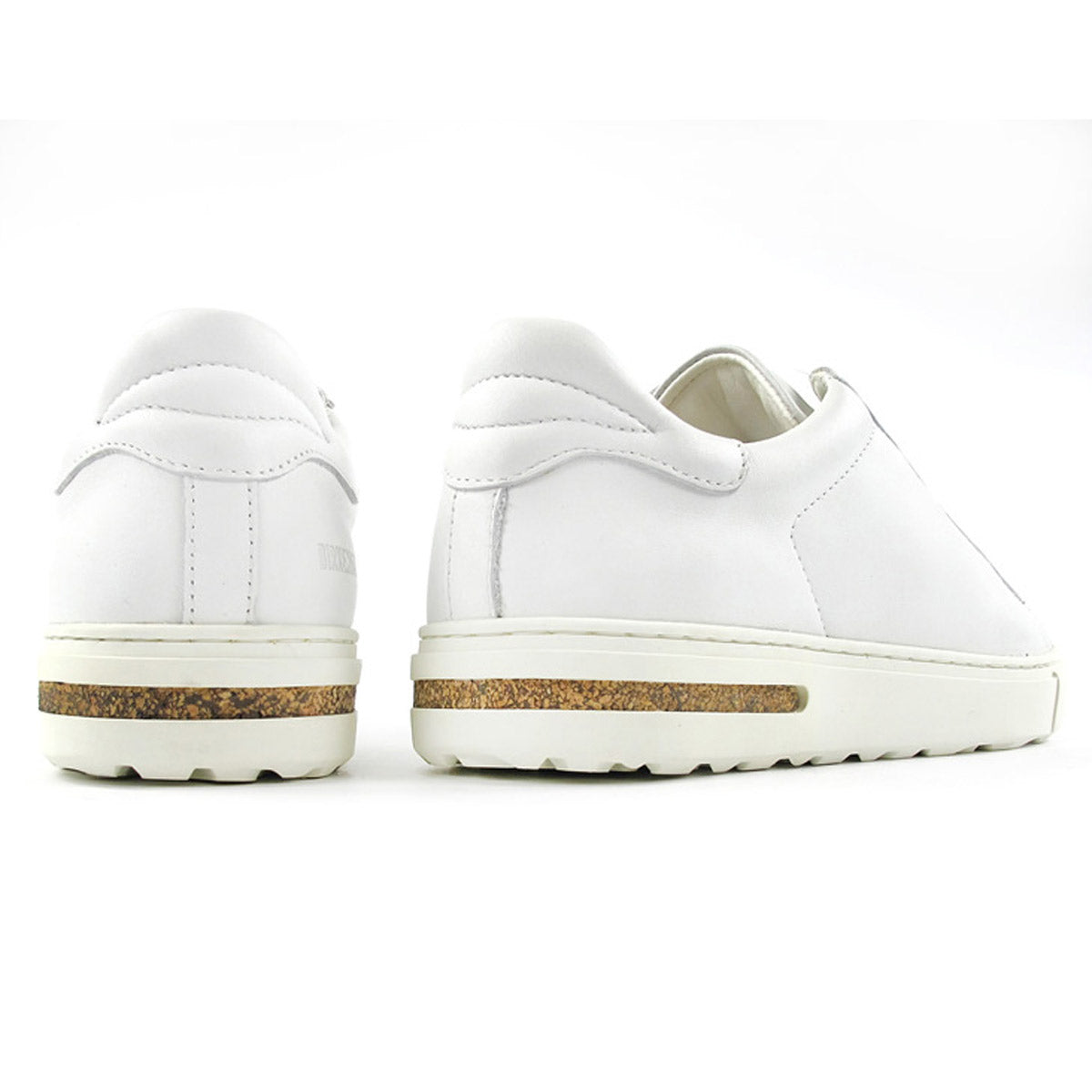 Rear view of a pair of BIRKENSTOCK BEND WHITE LEATHER - WOMENS with brown soles, displayed on a white background, showcasing their natural leather upper and the comfort of an anatomically shaped cork-latex footbed by Birkenstock.