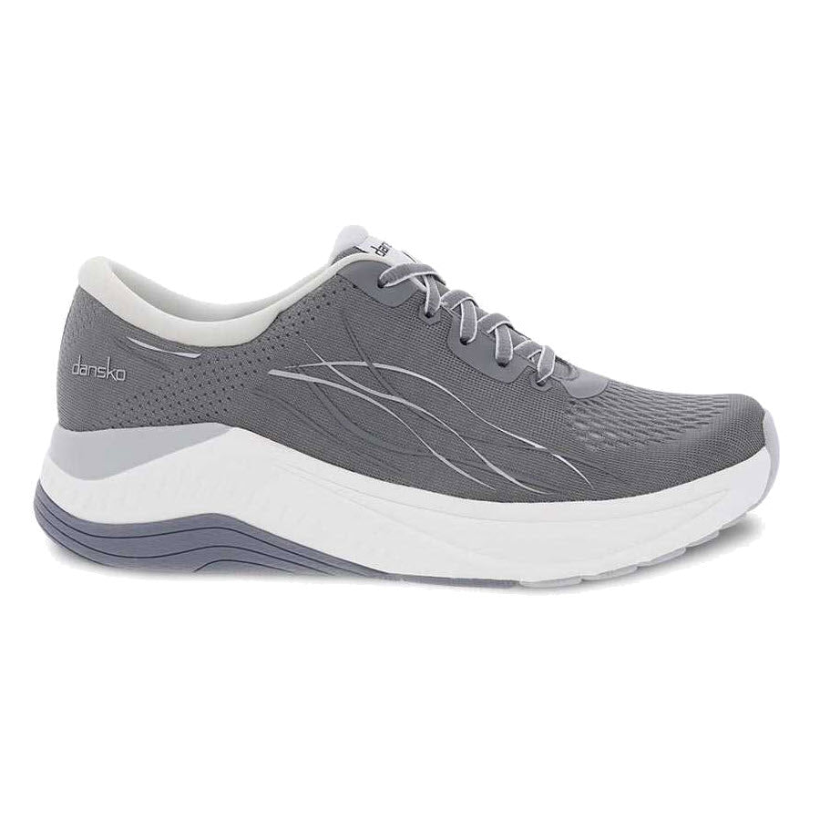 The Dansko Pace Grey Mesh walking shoe for women features white laces, a white sole, and a perforated design for breathability. The thick, cushioned midsole provides excellent support, while the Dansko Natural Arch Plus technology ensures enhanced comfort.