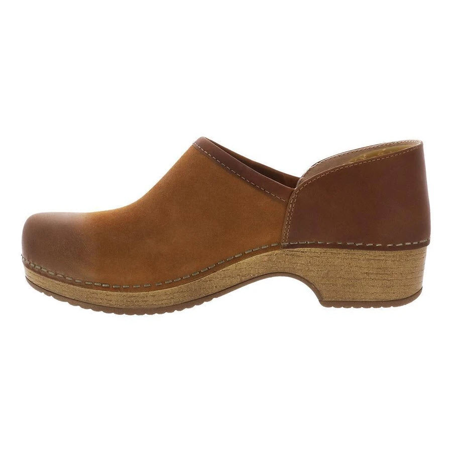 Side view of the DANSKO BRENNA TAN BURNISHED SUEDE - WOMENS, a brown leather slip-on shoe with a textured wooden sole and uniform stitching along the midsole, perfectly balancing style and comfort for a comfortable casual shoe.