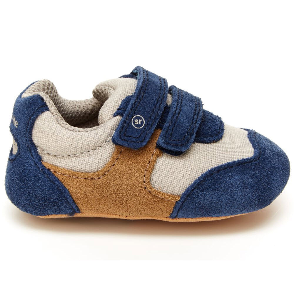 The Stride Rite Mason Navy/Truffle - Toddler is a small toddler shoe highlighting blue, beige, and brown fabric with two velcro straps over the top. Its Soft Motion Mason design ensures a comfortable fit for your baby's feet with memory foam insoles providing extra cushioning.