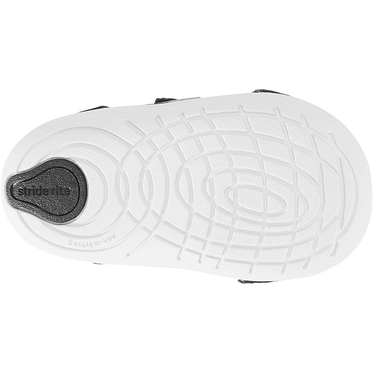 The image shows the sole of the Stride Rite SM Kennedy black kids&#39; athletic shoe, featuring a circular tread pattern and a black heel insert, complemented by memory foam insoles for extra comfort.