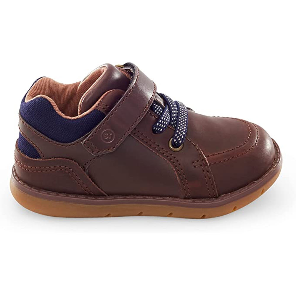 The STRIDE RITE ANDERS BROWN - KIDS sneaker by Stride Rite features a Velcro strap and laces, along with a light brown sole and navy blue accents. It is designed with comfy contoured construction, perfect for independent walkers.