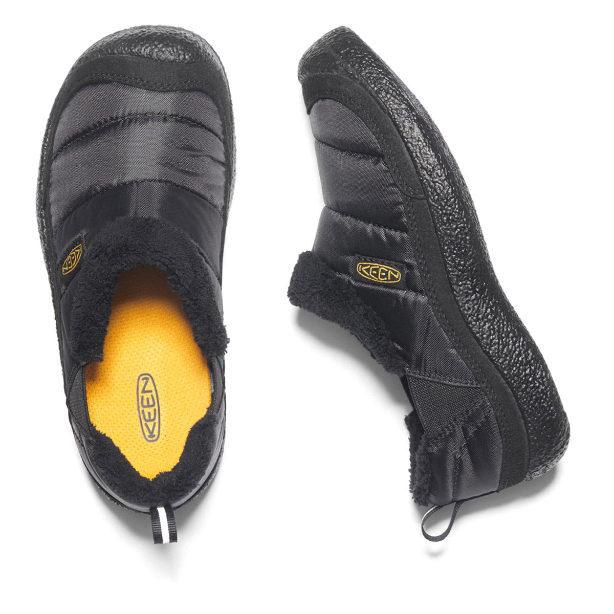 A pair of KEEN HOWSER II CHILD BLACK - KIDS slip-on shoes by Keen with black rubber soles, yellow insoles labeled &quot;Keen,&quot; and a quilted, puffy upper design, featuring natural odor control for ultimate freshness. Shown from the top and side, these slip-ons are the epitome of a comfy shoe.