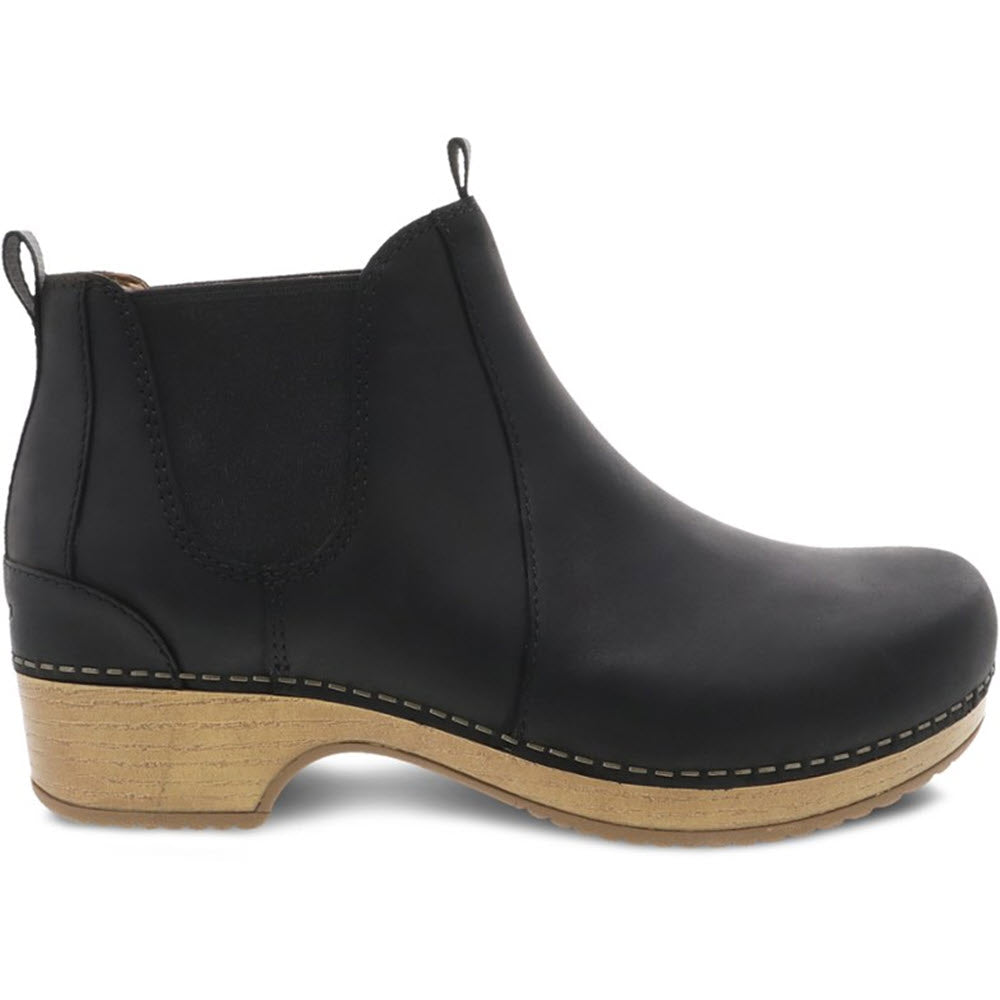 The Dansko DANSKO BECKA BLACK - WOMEN are black leather ankle booties with a low wooden heel and black elastic side panels, perfect for any chic ensemble.