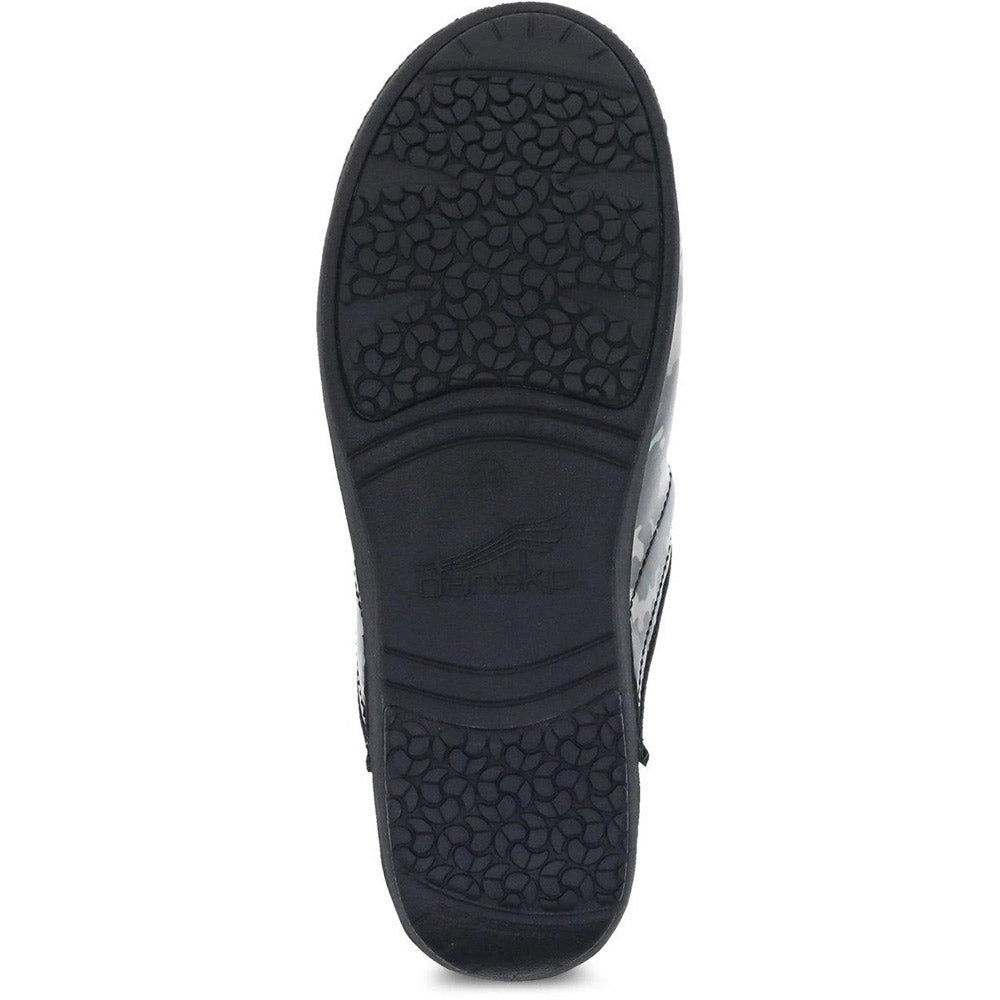 The image shows the sole of a black Dansko shoe with a textured pattern for grip or traction, featuring a slip-resistant outsole ideal for stability. The product is the DANSKO PRO XP 2.0 CAMO PATENT - WOMENS.