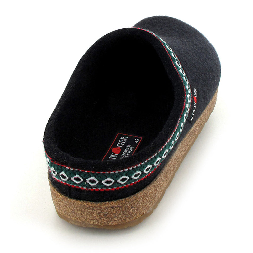 The Haflingers HAFLINGER GZ BLACK - ADULTS is a black slip-on wool clog featuring an anatomical cork footbed with a slip-resistant rubber sole, accentuated by red and green patterned trim around the opening.