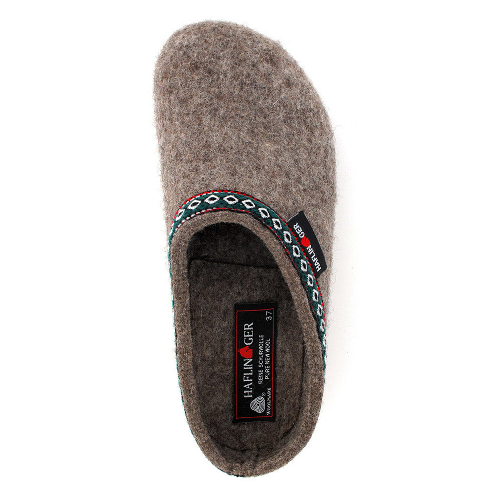 A top view of a single grey Haflingers HAFLINGER GZ EARTH - WOMENS slipper with a woven decorative trim along the opening, brand tags on both the interior label and exterior side, and an anatomical cork footbed.