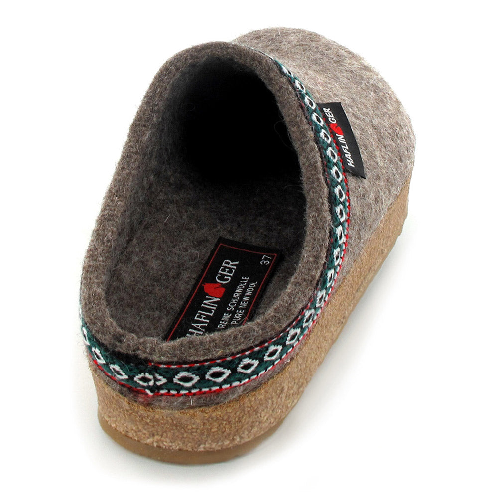 A single grey Haflingers HAFLINGER GZ EARTH - WOMENS slipper with a brown cork footbed and patterned trim at the opening showcases its wool felt upper against a white background, evoking an Alpine style charm.