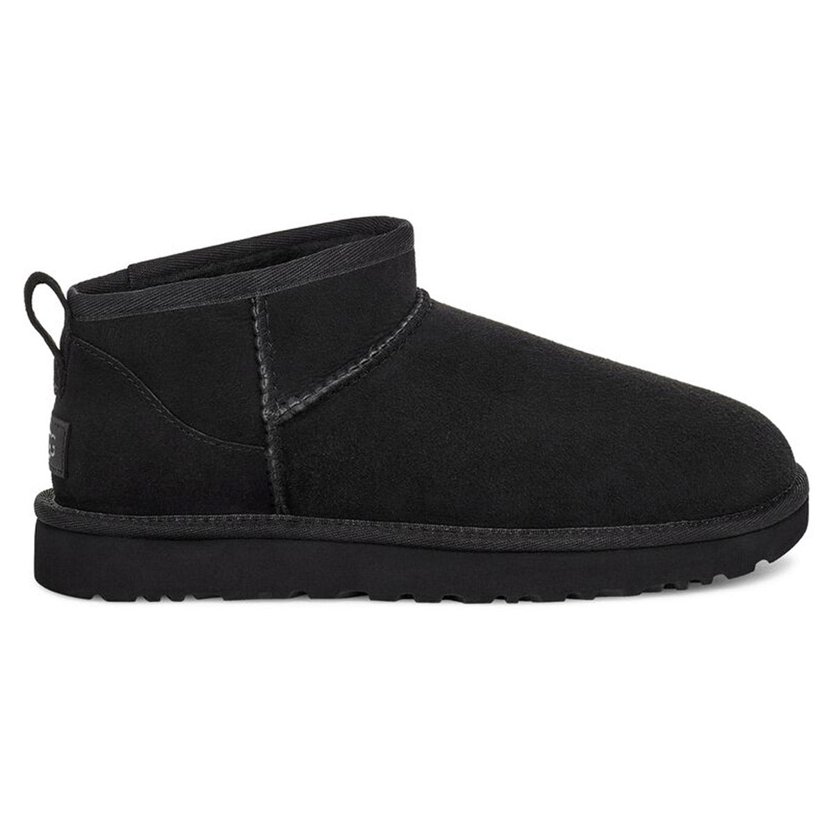 The UGG CLASSIC ULTRA MINI BLACK - WOMENS by Ugg is a black suede ankle-high boot with visible stitching and a pull tab on the back. Featuring Twinface sheepskin and a thick, ridged Treadlite by UGG sole, it’s designed for cold weather.