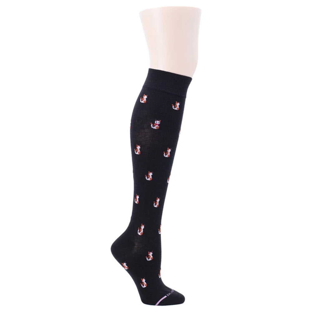 A DR. MOTION COMPRESSION SOCK CATS BLACK sock, from Dr. Motion, with a pattern of small white and red cats, crafted from a breathable cotton blend for added comfort, displayed on a mannequin leg.