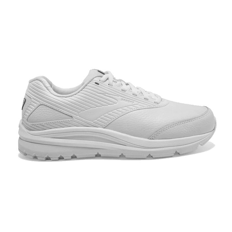 The Brooks Addiction Walker 2 Lace White for women is displayed in a side profile view, featuring a white walking shoe with a textured pattern, lace-up closure, and a thick, grooved outsole for added stability.