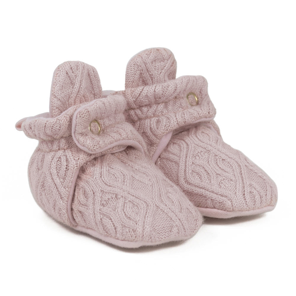 Introducing the Robeez Snap Booties Light Pink Sweater Knit - Toddlers: a pair of pink knitted baby booties featuring a delicate diamond sweater knit pattern, secured with a buttoned strap near the ankle. Perfectly cozy for your baby's feet.