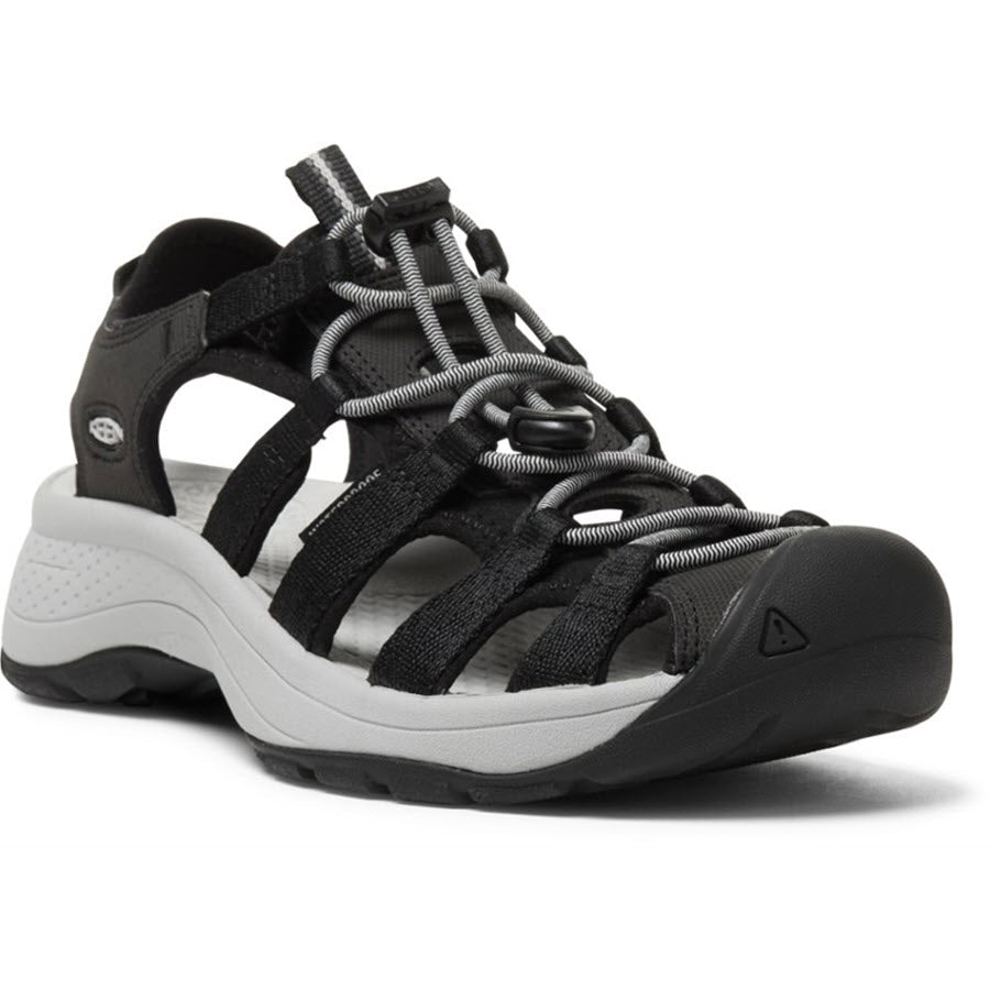 The KEEN ASTORIA WEST BLACK - WOMENS by Keen is a black hybrid adventure sandal with a reinforced toe, grey accents, and a rugged sole. It features adjustable straps and a cushioned footbed for optimal comfort, along with a slip-resistant grip for added stability.