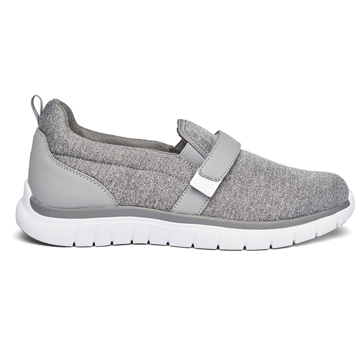 The Anodyne Sport Trainer Grey for women is a stylish gray slip-on sneaker with a white sole, featuring a fabric upper and a Velcro strap across the top. It also includes a dual insole system for added comfort.