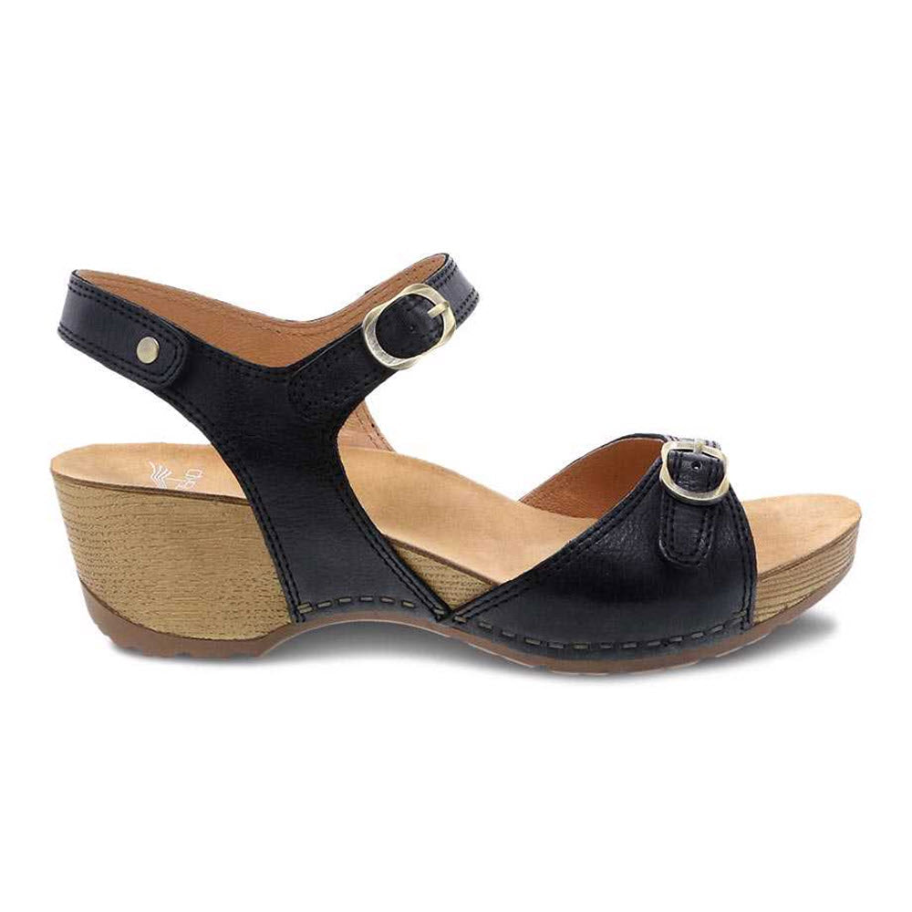 The DANSKO Tricia Black Milled Burnished Women&#39;s sandal by Dansko features black leather uppers, adjustable ankle and toe straps with silver buckles, and a wooden heel. Designed for all-day comfort.