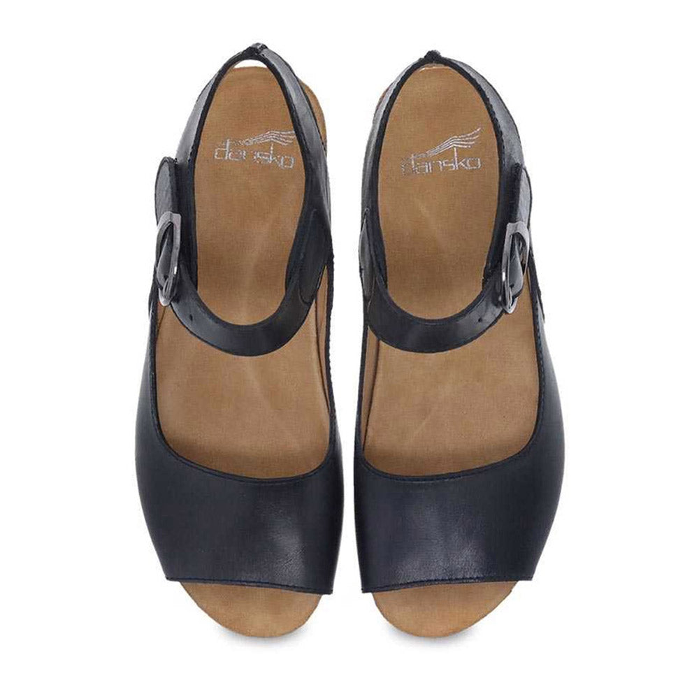 A top-down view of the Dansko Tiana Black Burnished women&#39;s shoe reveals its open-toe design, ankle straps, and buckles, all embodying the classic comfort of this elegant Dansko footwear.