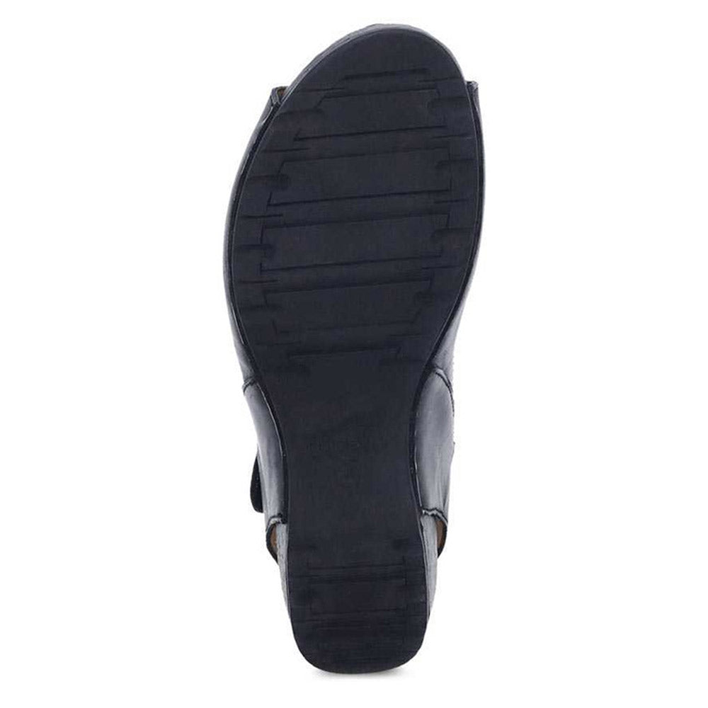 The image shows the sole of a Dansko Tiana Black Burnished women&#39;s shoe, featuring a textured pattern and a slight heel.