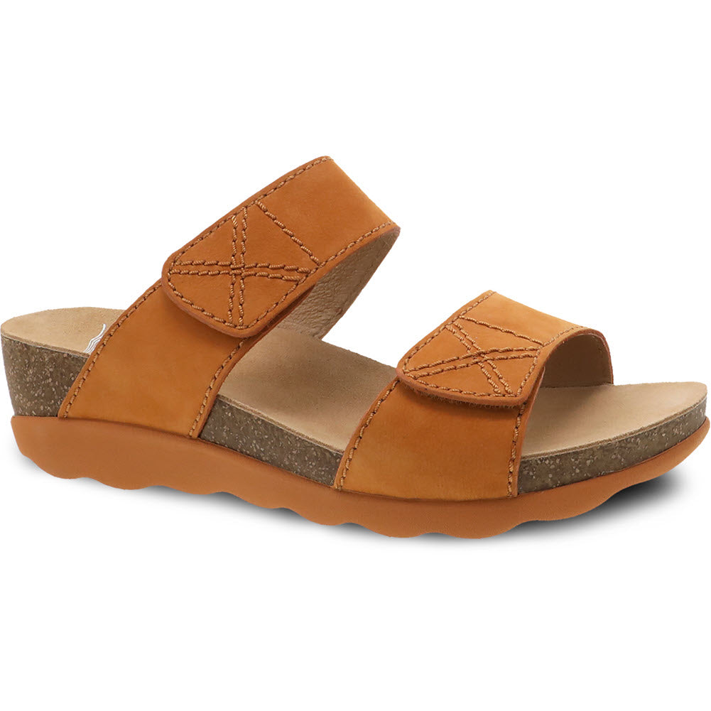 The DANSKO MADDY ORANGE MILLED NUBUCK - WOMENS by Dansko is a women&#39;s sandal featuring two crisscross, adjustable straps, a lightweight cork midsole, and a rugged orange sole.