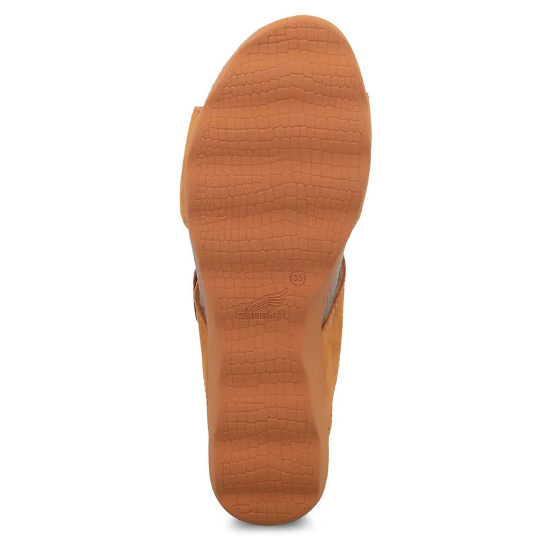 A close-up view of the bottom sole of an orange milled nubuck women&#39;s sandal, Dansko Maddy, featuring a textured pattern and the Dansko logo, with adjustable straps for a secure fit.