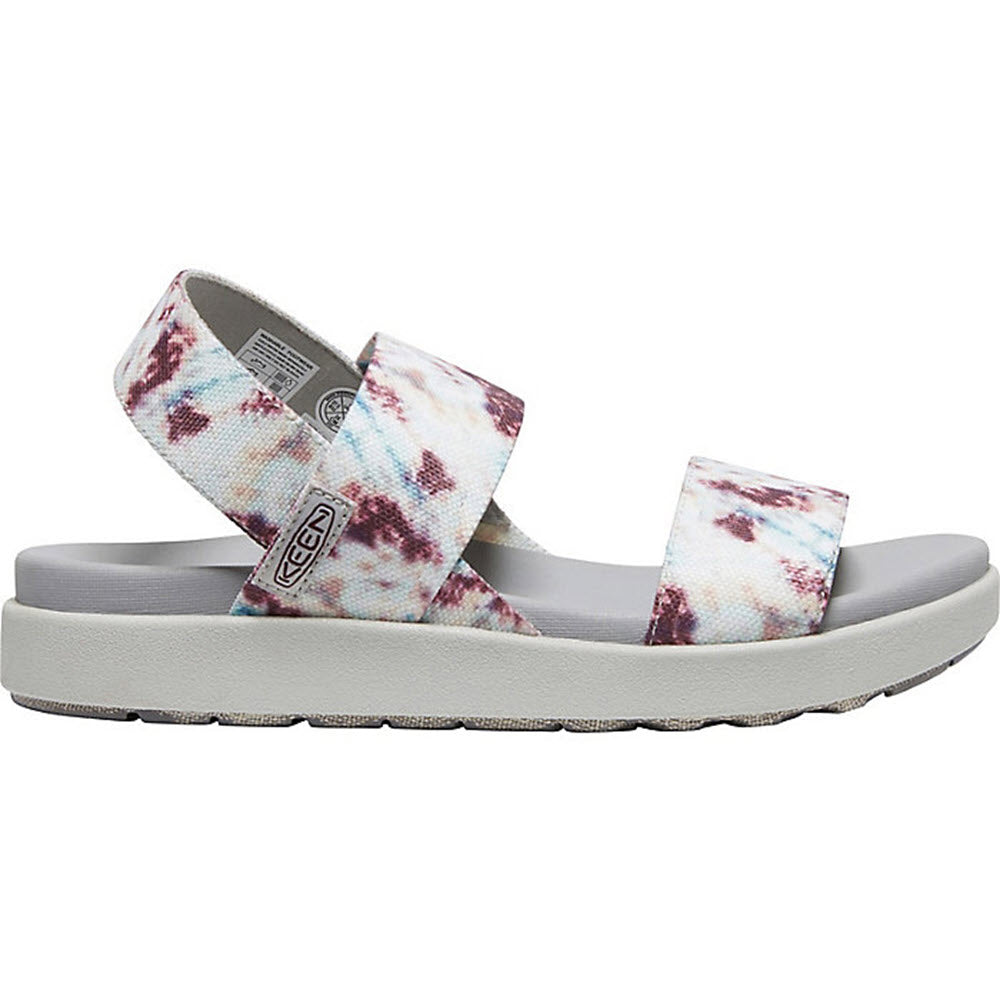 Side view of the KEEN Elle Backstrap Andorra Tie Dye - Women&#39;s sandal featuring two fabric straps, an eco-friendly design, a cushioned gray footbed, and a thick white sole.