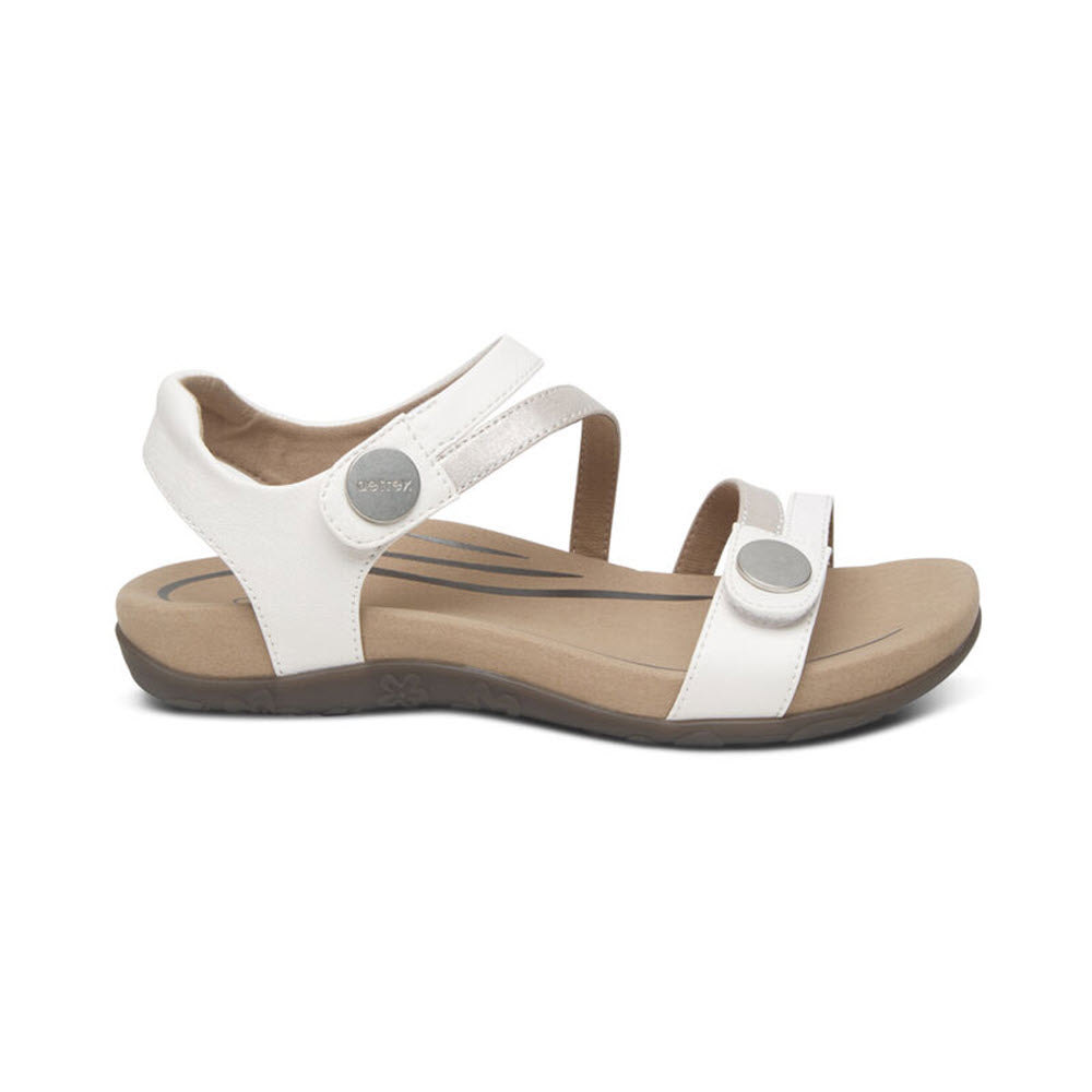 Aetrex AETREX JESS WHITE - WOMENS is a white open-toe sandal with an adjustable ankle strap and a cushioned memory foam footbed. The outsole is dark beige and has a textured grip pattern.