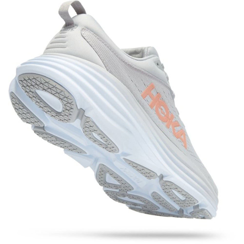 A white and light gray athletic shoe with a thick sole and peach-colored &quot;Hoka&quot; logo on the side, shown from a bottom-up perspective, exemplifies the HOKA ONE ONE Bondi 8 Harbor Mist/Lunar Rock - Women&#39;s dedication to foot health through its ultra-cushioned design.