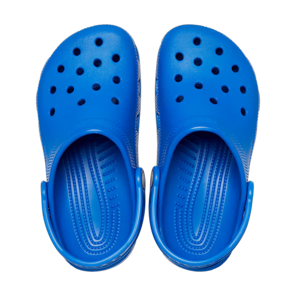 A pair of CROCS CLASSIC CLOG BLUE BOLT - KIDS with perforated holes on the top and adjustable heel straps, viewed from above, showcasing Iconic Crocs Comfort.