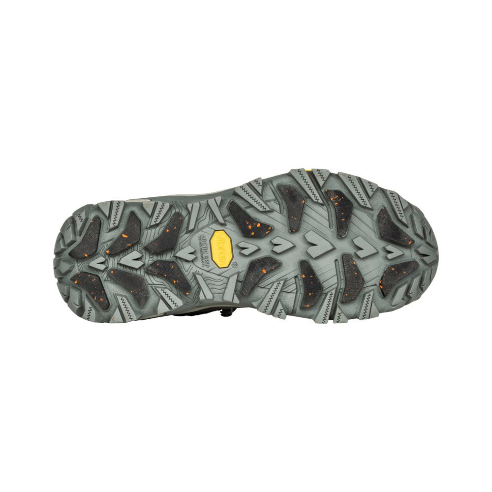 The image shows the outsole of a women&#39;s hiking boot with aggressive tread patterns and a yellow logo at the center. The tread design features angular, multidirectional lugs for enhanced traction, making it perfect for winter weather. The product showcased is the Oboz OBOZ BANGTAIL MID INSULATED BDRY WINTER QUARTZ - WOMENS.