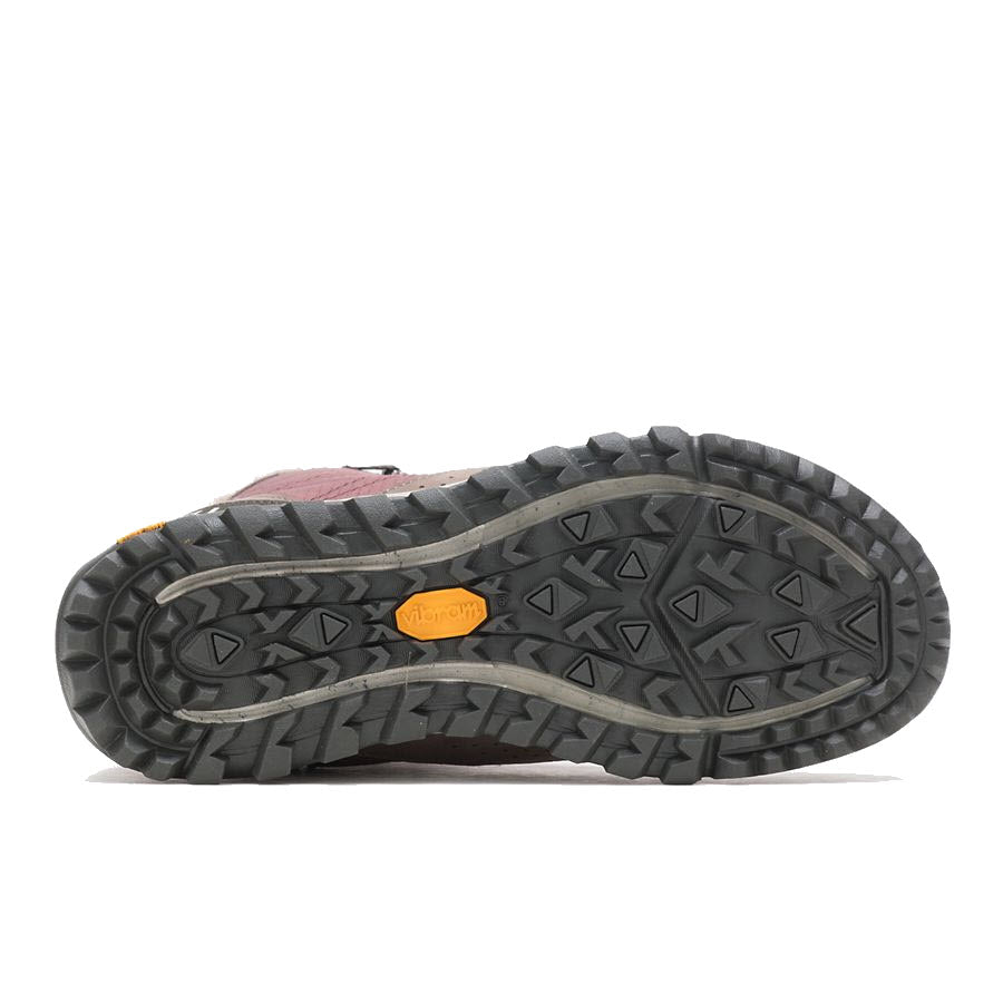 The image depicts the sole of the MERRELL ANTORA SNEAKER BOOT MARRON - WOMENS by Merrell, featuring a distinctive tread pattern and a yellow Vibram logo at the center, highlighting its durability ideal for cold-weather treks.