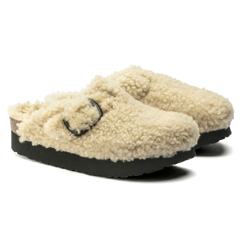 A pair of Birkenstock Boston Platform Big Buckle Teddy Eggshell Shearling slip-on sandals for women, featuring beige fleece-lining, black adjustable buckles, a thick platform sole, and a cozy teddy style.