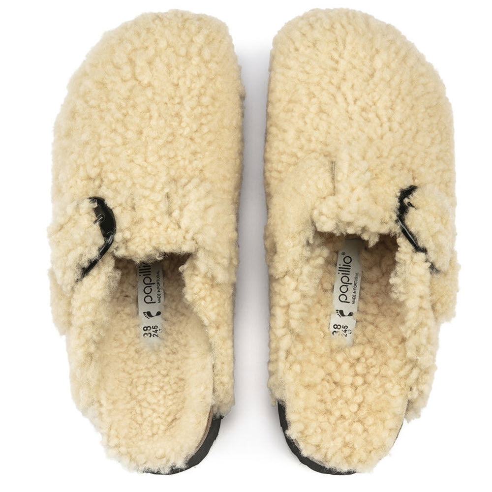 Top view of a pair of Birkenstock BOSTON PLATFORM BIG BUCKLE TEDDY EGGSHELL SHEARLING slippers, featuring an ankle strap and black buckle, labeled &quot;Papillio&quot; on the sole tags.