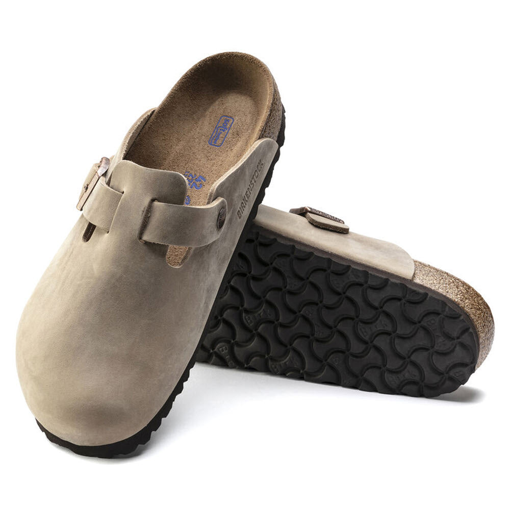 A pair of BIRKENSTOCK BOSTON TOBACCO LEATHER - ADULTS slip-on clogs with black rubber soles, featuring an adjustable strap and a soft footbed for ultimate comfort.