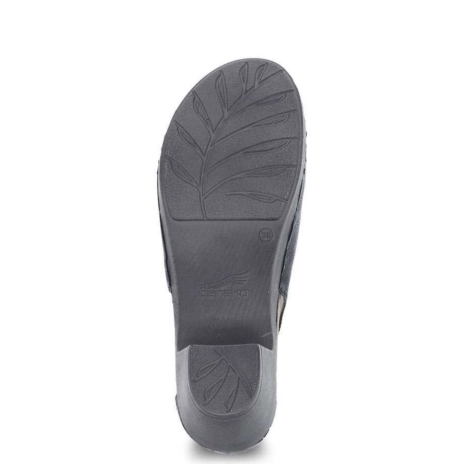 A single black shoe sole with a leaf pattern and the brand name &quot;Dansko&quot; embossed in the center, featuring Dansko Natural Arch Technology for enhanced comfort.