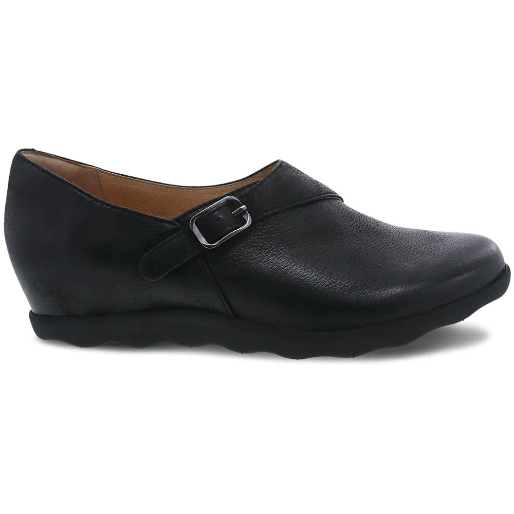 The DANSKO MARISA BLACK BURNISHED - WOMENS by Dansko is a black leather wedge slip-on shoe that features a buckle strap on the side, a textured sole, and a comfortable memory foam footbed.