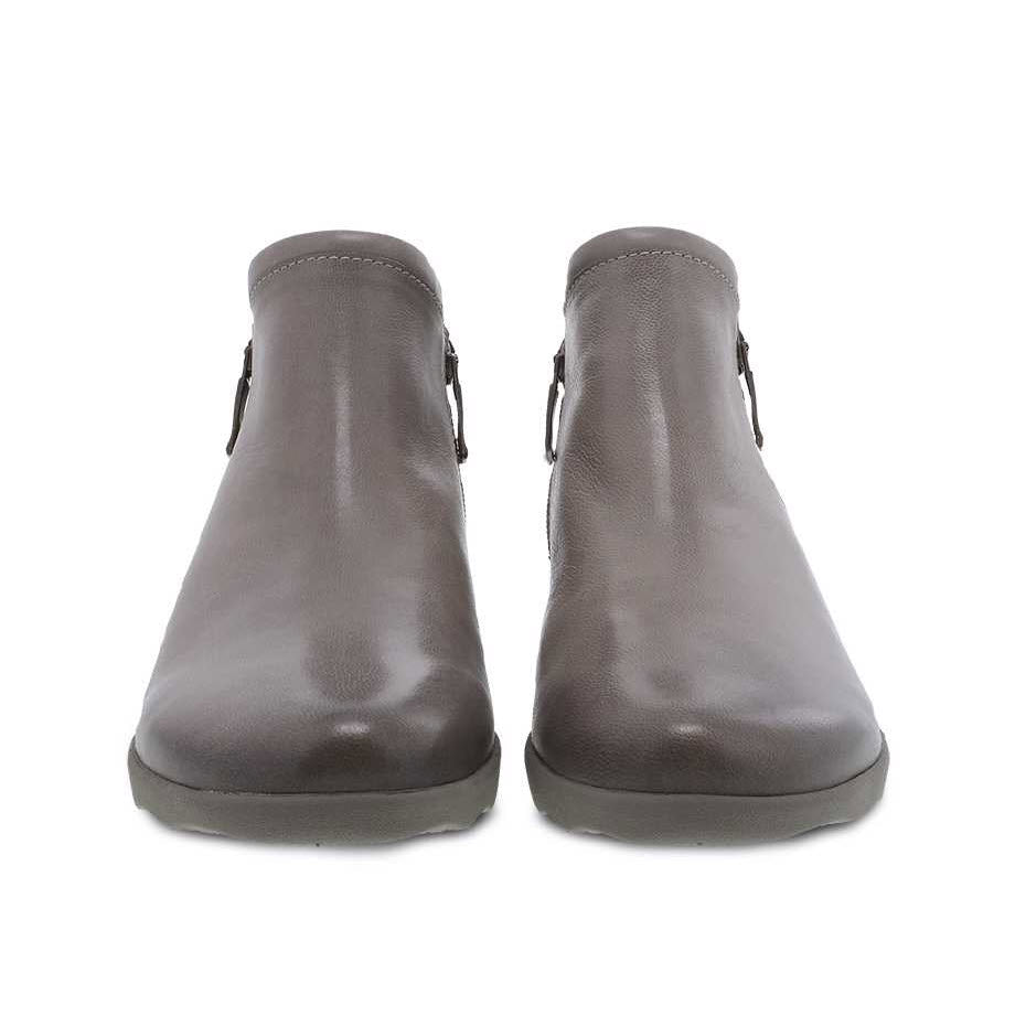 The DANSKO MIKI TAUPE BURNISHED - WOMENS ankle boots in gray leather feature side zippers and are displayed from the front. They boast Dansko&#39;s Natural Arch technology along with a removable PU footbed for enhanced comfort, effortlessly blending style and function for casual wear.