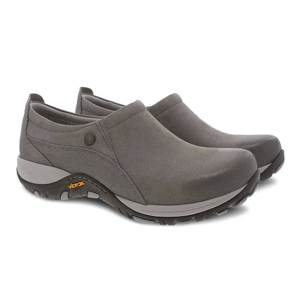 Introducing the Dansko Patti Taupe Burnished for women: a pair of slip-on shoes featuring a rugged, slip-resistant rubber sole and small button detail. Ideal for outdoor activities, these shoes also showcase the iconic Vibram logo on the side.