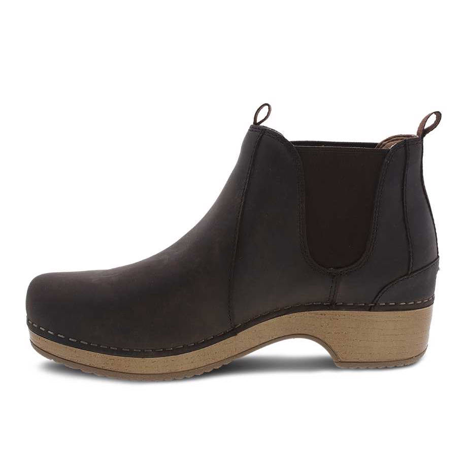 A single dark brown ankle boot with a low wooden heel, featuring side elastic panels and a pull loop at the back, perfect for your fall/winter wardrobe. The DANSKO BECKA BROWN - WOMENS by Dansko ensures both comfort and chic elegance.