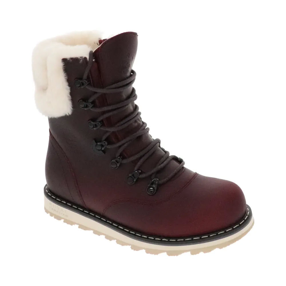 The ROYAL CANADIAN CAMBRIDGE BURGUNDY - WOMENS by Royal Canadian is a waterproof leather winter boot in maroon, featuring a white fur lining, black laces, a tan sole with white stitching, and shown from an angled side perspective.