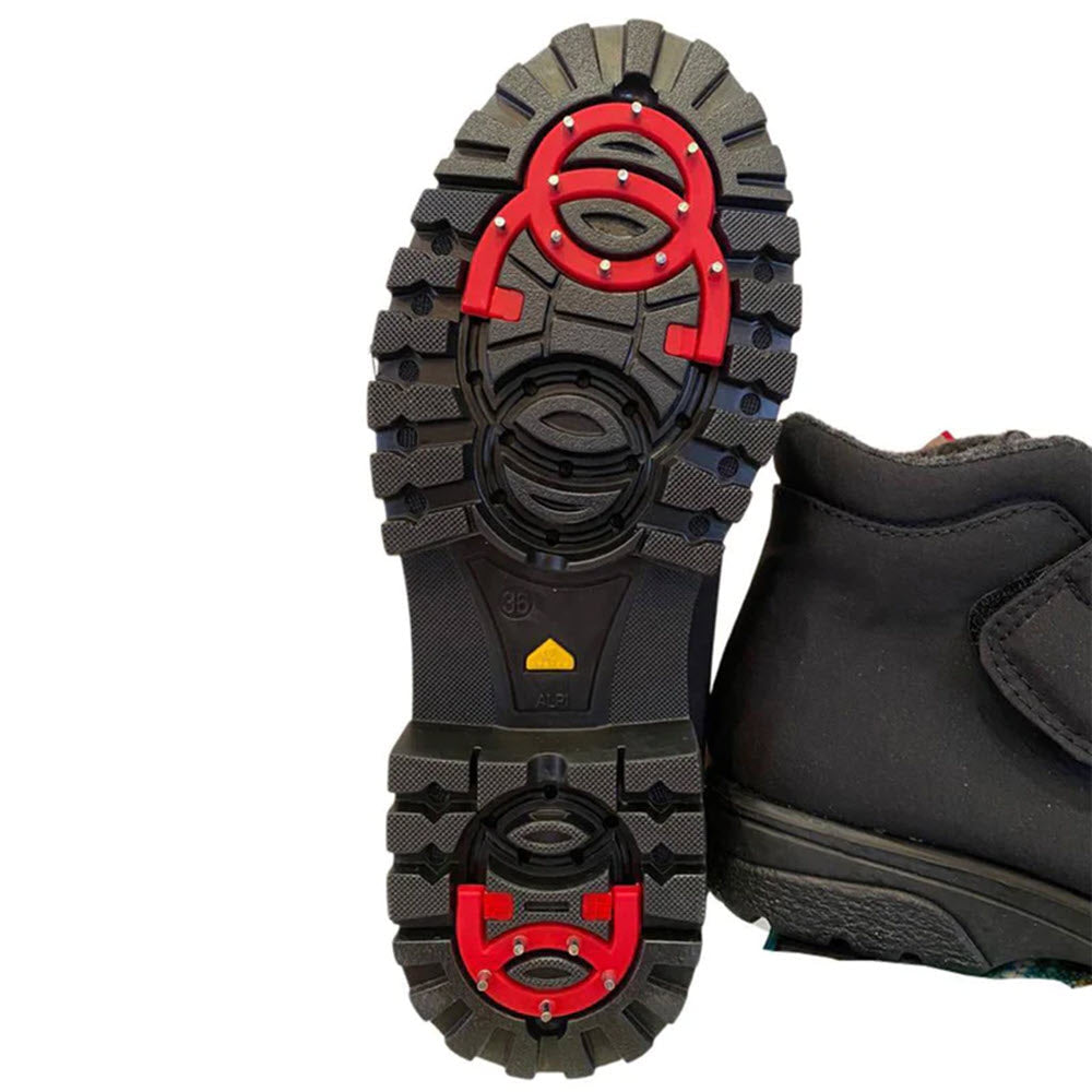 Close-up view of the sole of a Toe Warmers TOE WARMERS AVA FLIP GRIP BLACK - WOMENS winter boot featuring a rugged tread pattern with red and yellow accents, designed for enhanced grip and stability.