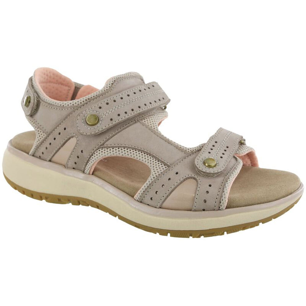 The SAS EMBARK SANDAL TAUPE - WOMENS by SAS is a beige outdoorsy sandal featuring an open-toe design, adjustable Velcro straps, brass button details, and a cushioned insole along with a durable beige rubber sole.