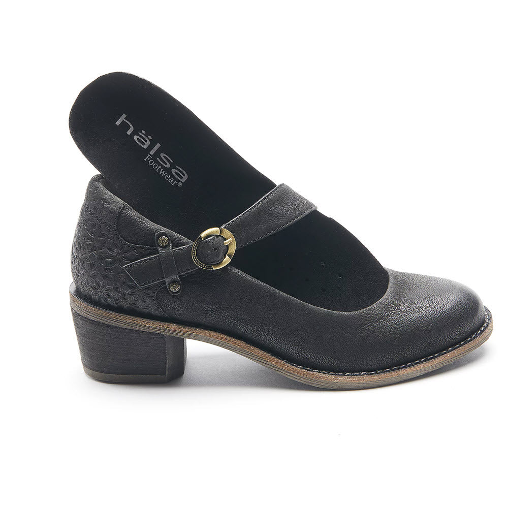 A black low-heeled Mary Jane shoe with an adjustable buckle strap, featuring a retro-inspired silhouette and text that reads &quot;Halsa Footwear&quot; on the insole, known as HALSA MIA BLACK - WOMENS by Halsa.