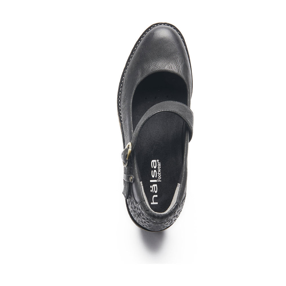 A single heeled Mary Jane shoe with a strap and buckle detail, featuring a retro-inspired silhouette and labeled &quot;Halsa&quot; on the insole, viewed from above on a white background. This shoe is identified as the HALSA MIA BLACK - WOMENS.