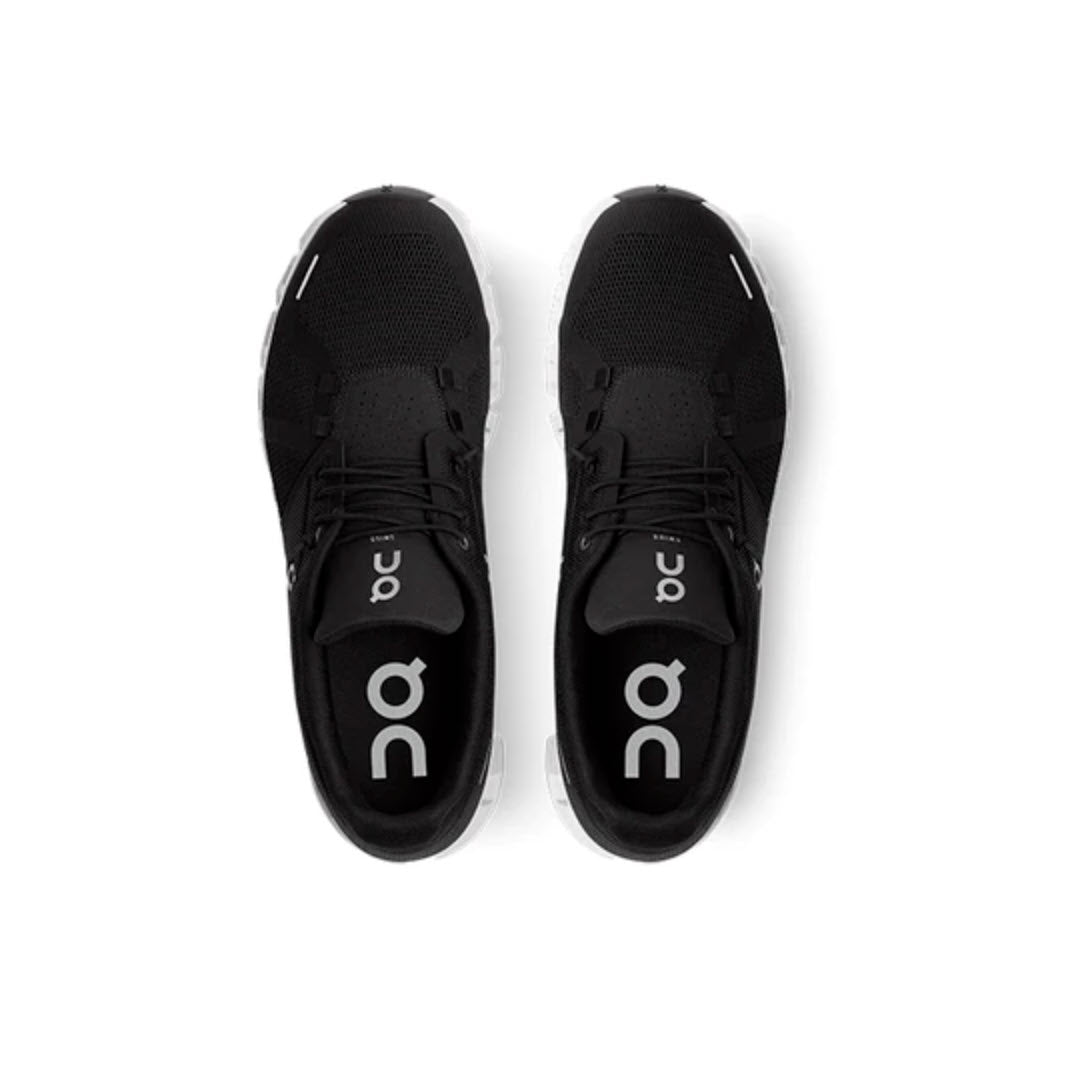 Top view of a pair of ON CLOUD 5 BLACK/WHITE - MENS athletic shoes by On Running with white soles, featuring the brand logo and text. Enhanced with a speed lacing system, they are positioned side by side on a white background, promising both style and convenience.