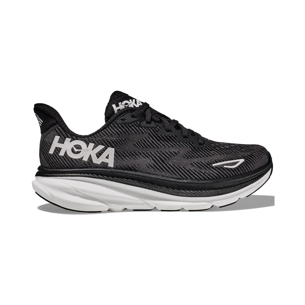 The HOKA CLIFTON 9 BLACK/WHITE - WOMENS running shoe by Hoka features breathable mesh uppers, a cushioned white sole, and a prominent HOKA logo on the side.